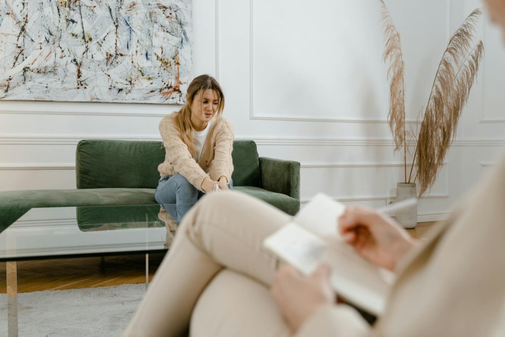A woman during a therapy session in a modern living room setting, expressing concern.